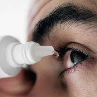Man applying eye drops into eye, extreme close-up